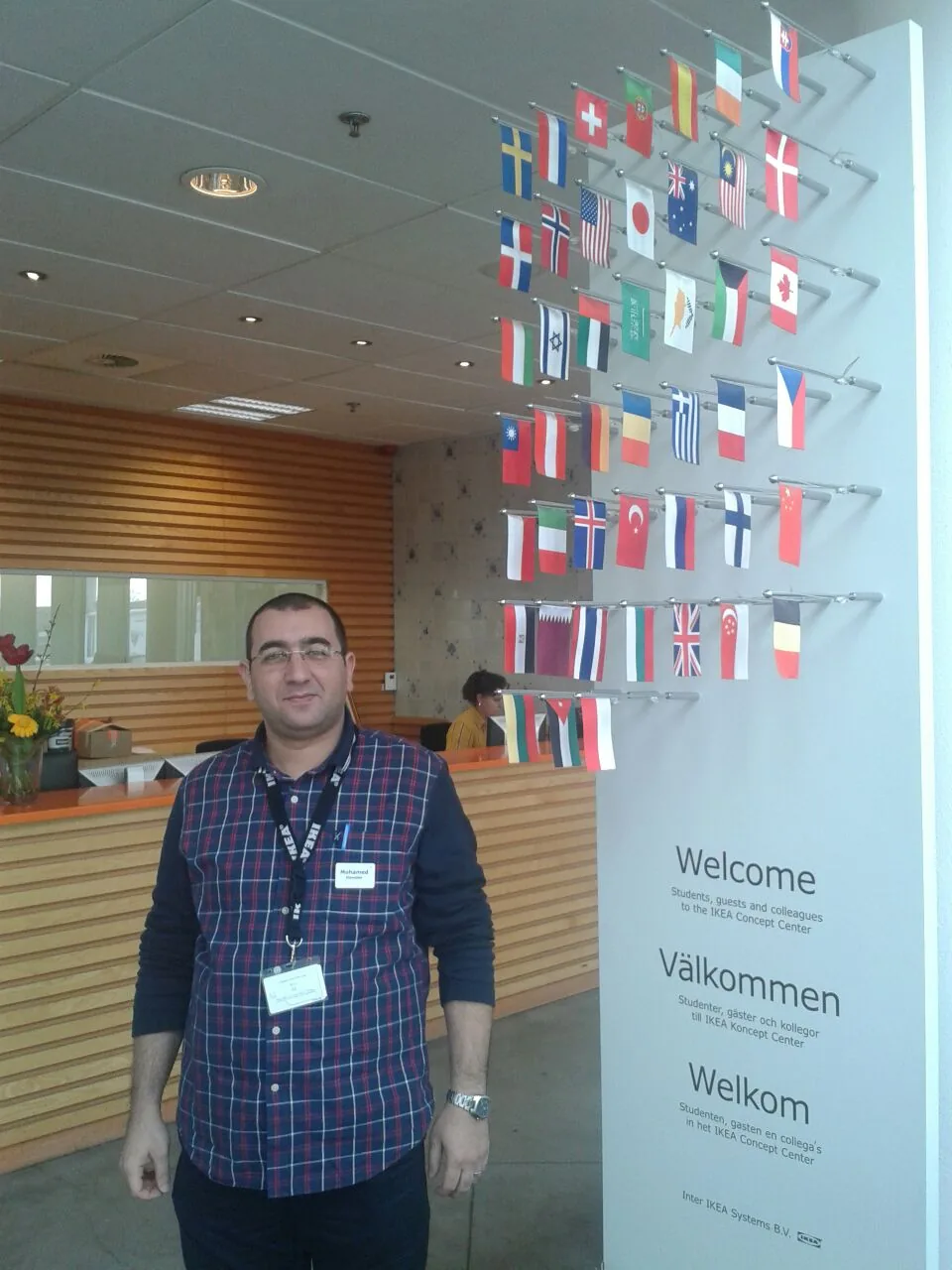 Mohamed Alawdan at the IKEA Concept Center in Delft, beside the welcome wall and its national flags